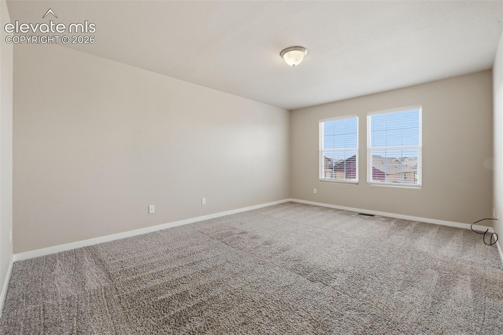 Multiple windows bring natural light into the spacious primary bedroom.