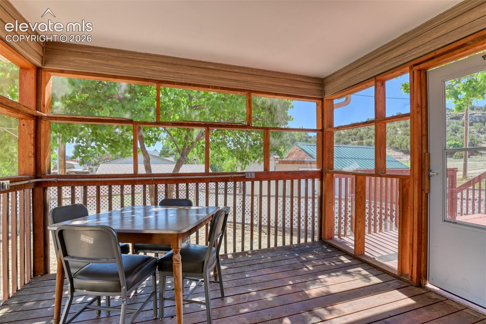 Screened-in porch featuring exposed wood framing, wood-plank flooring, and vertical balusters
