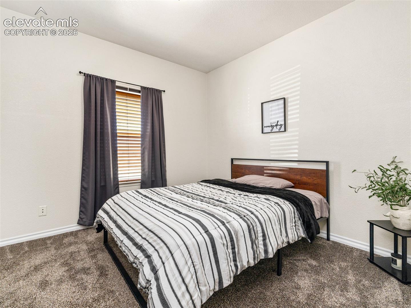 Carpeted flooring, a window with horizontal blinds, and neutral wall tones