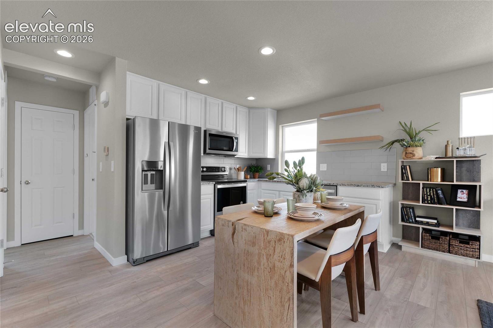 Kitchen featuring stainless steel appliances, white cabinetry, light wood-finish flooring, and recessed lighting
*photos of a model home*