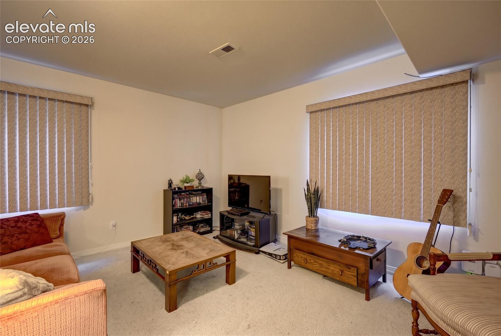 Neutral-toned carpeting and dual windows featuring vertical blinds