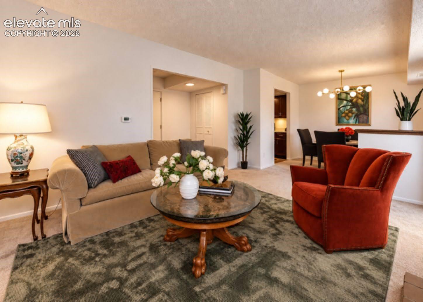 Living area featuring neutral wall-to-wall carpeting and a modern tiered chandelier with globe-style bulbs