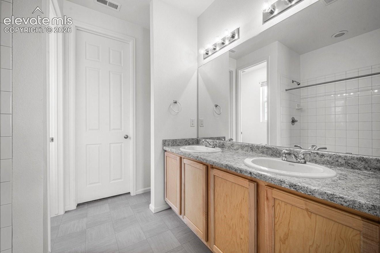 Double vanity with laminate countertops, wood-finish cabinetry, and white porcelain sinks
