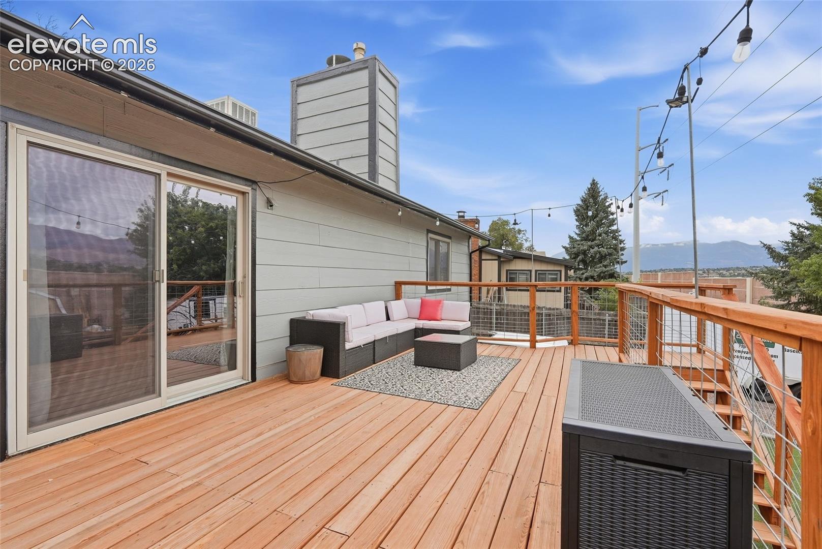 Spacious deck featuring wood decking, a cable railing system, and a sliding glass door