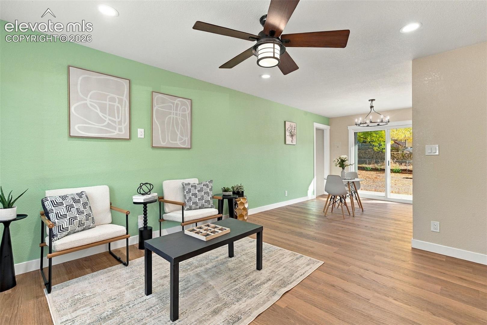 Interior space featuring wood-finish flooring, recessed lighting, a ceiling fan with integrated light fixture, a dedicated multi-light chandelier, and glass sliding doors