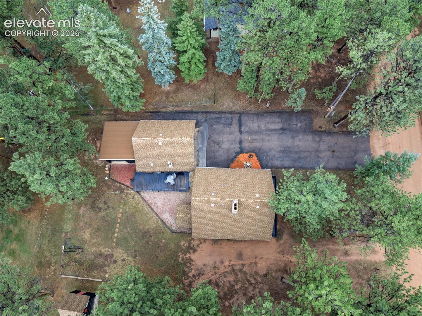 Asphalt shingle roofing, mature trees, and an asphalt driveway