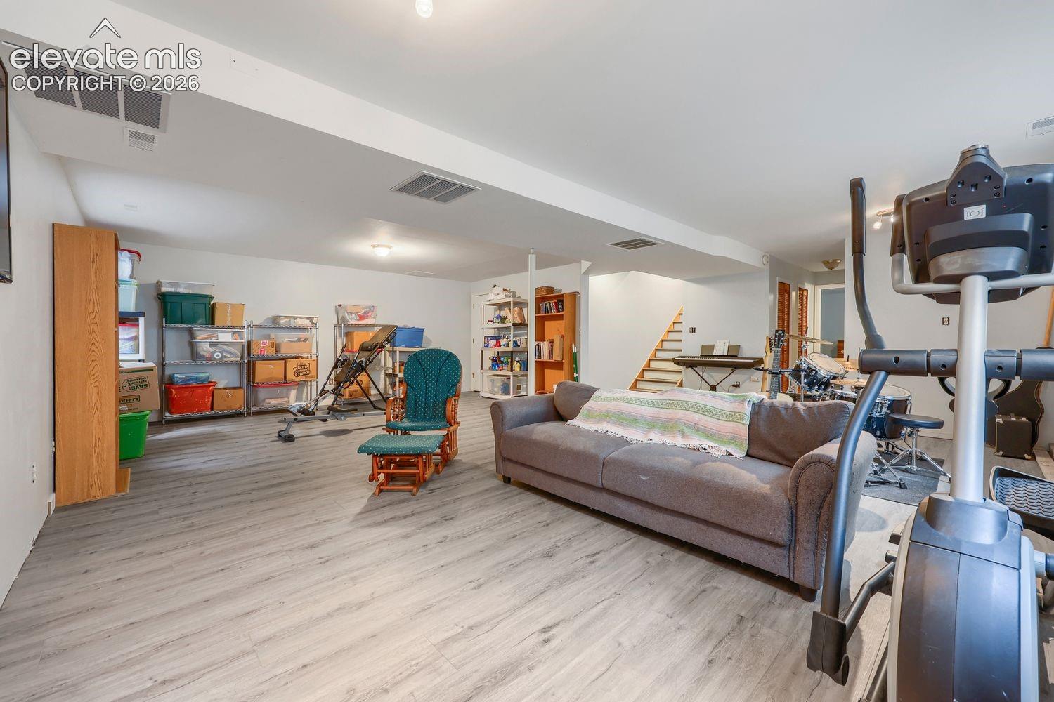 Spacious lower-level room featuring wood-finish flooring, recessed lighting, and a built-in staircase