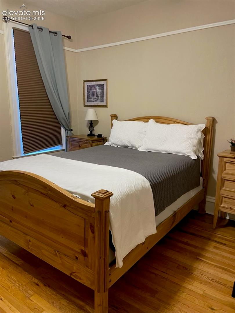Hardwood flooring, painted walls, crown molding, and a window with blinds