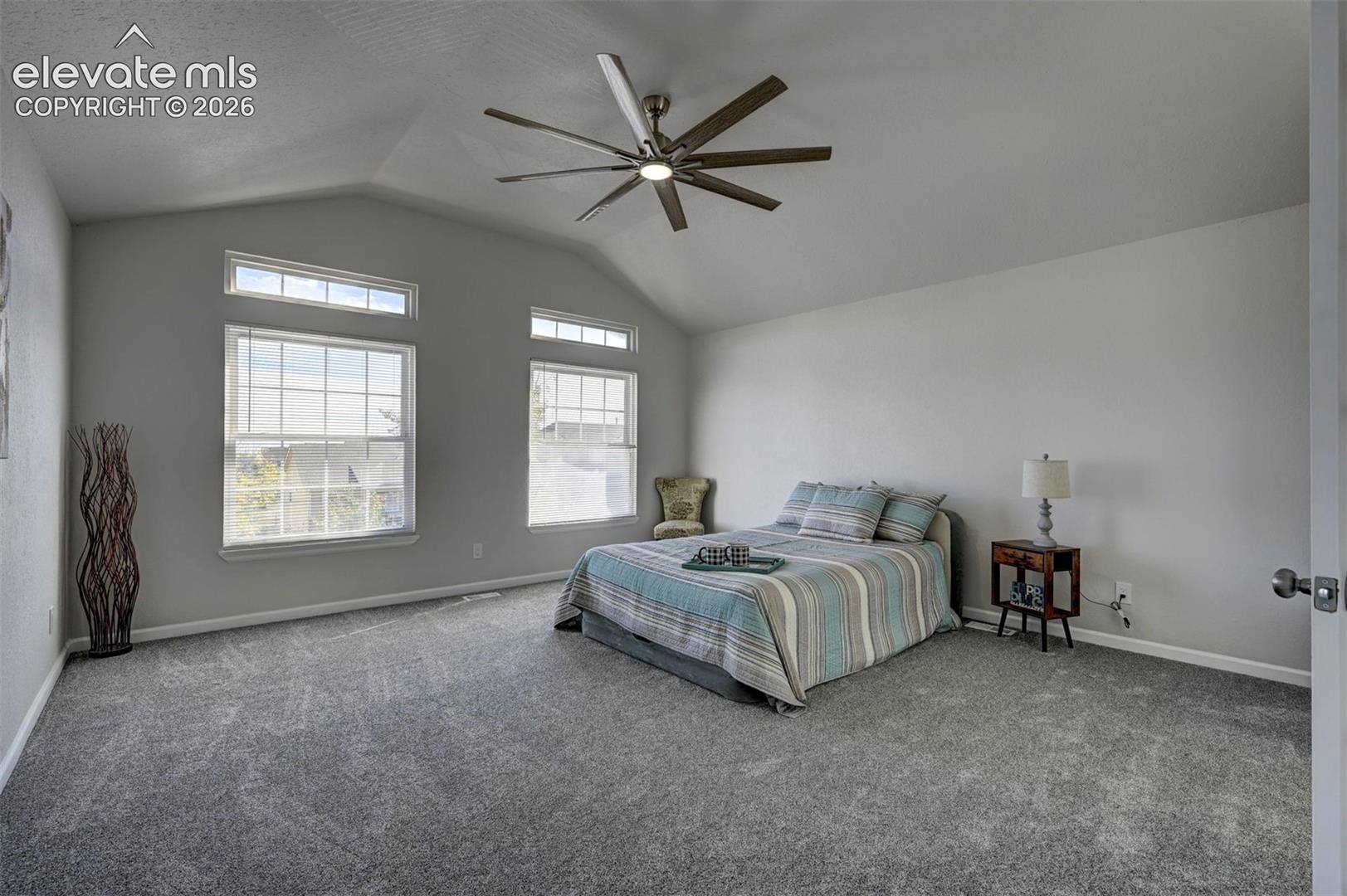 Vaulted ceilings featuring a multi-blade ceiling fan with integrated lighting and dual sets of windows with transoms