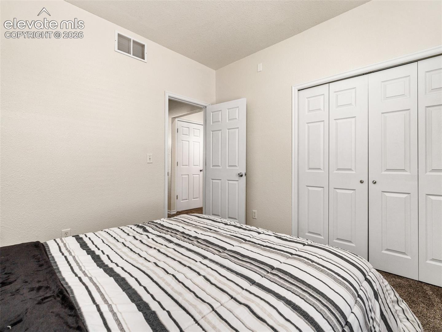 Neutral wall color, textured ceiling, white trim, white paneled doors, and carpeted flooring