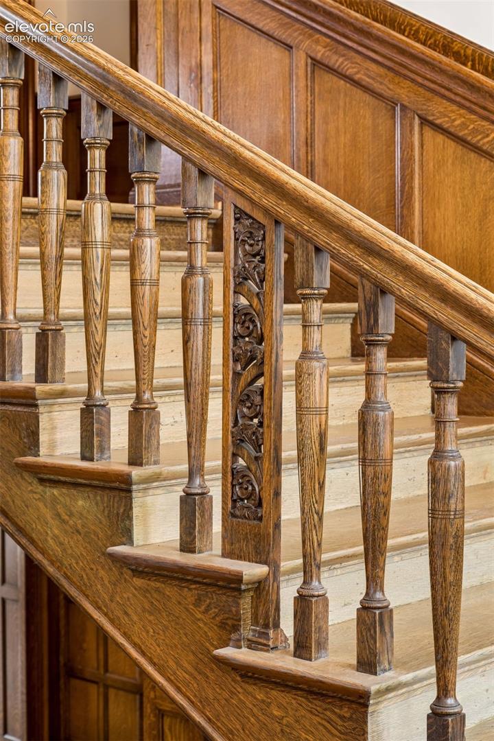 The newel posts are carved in a bell flower pattern, and the balustrades feature a unique leaf design set between thin twin balusters alternating with spindles.
