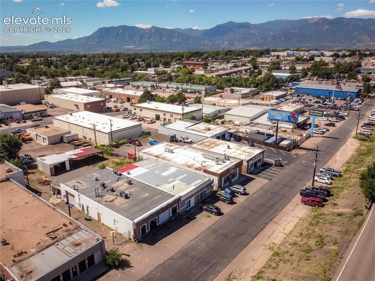 Commercial buildings with flat roofs, paved parking areas, and surrounding mountains