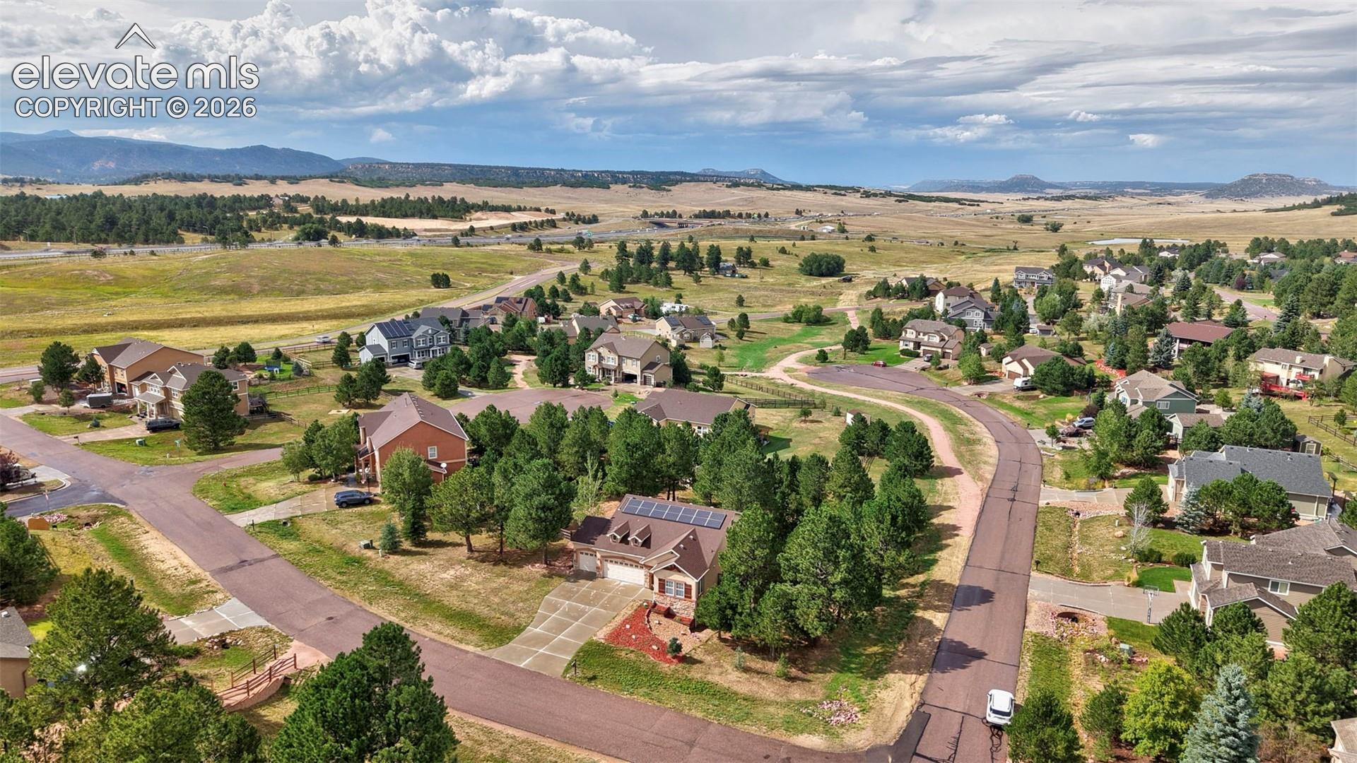 Residential properties with varied architectural styles, mature trees, and mountainous scenery
