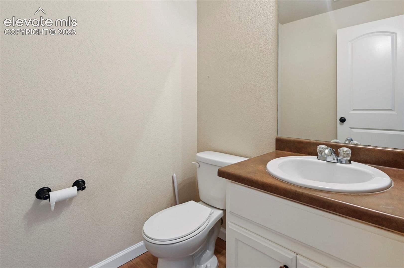 Bathroom featuring a white vanity cabinet, solid-surface countertop with an integrated oval basin, polished chrome hardware, and a wall-mounted mirror