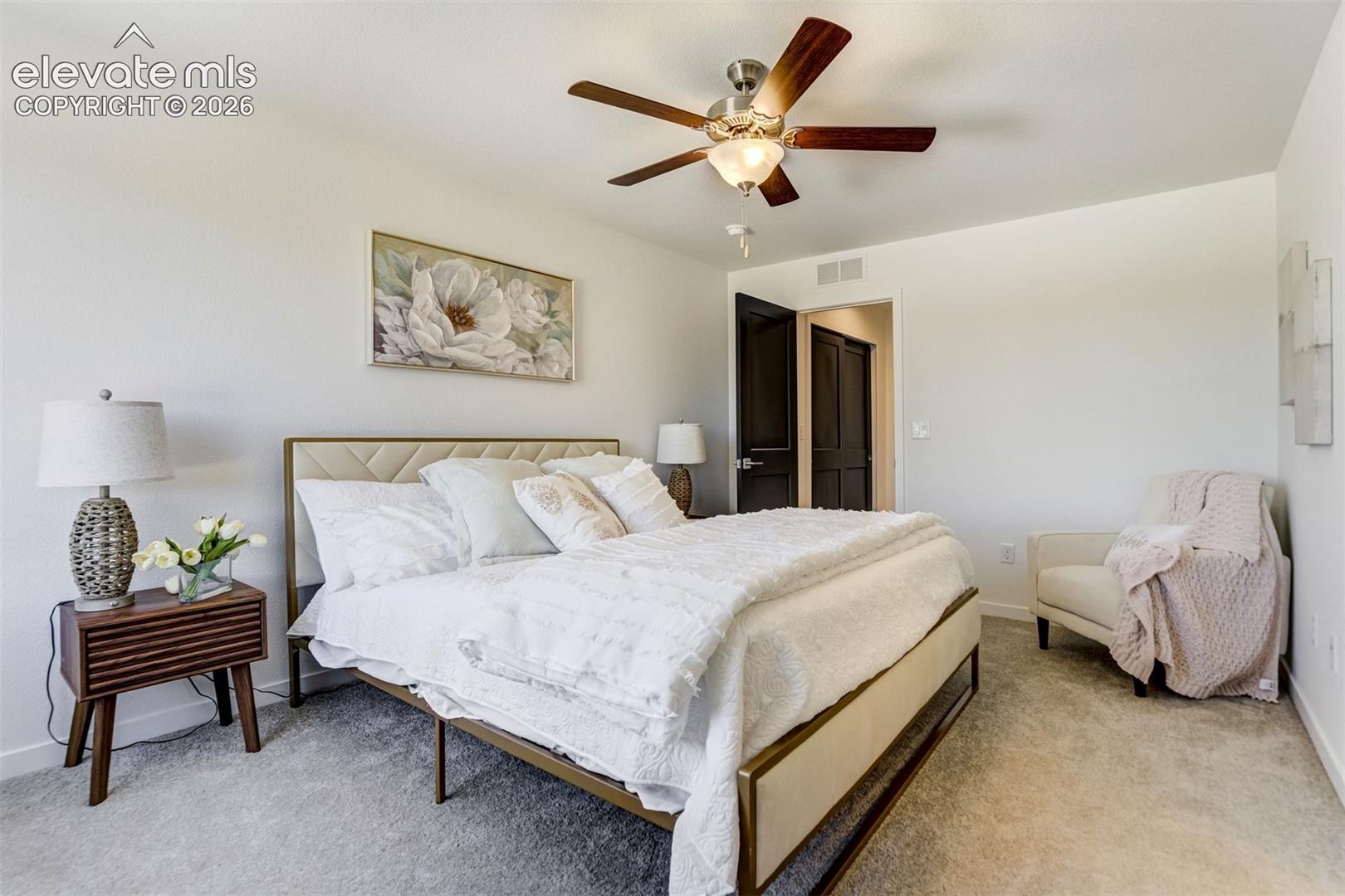 Neutral-toned carpeting, multi-blade ceiling fan with integrated lighting, and dark-finish interior doors