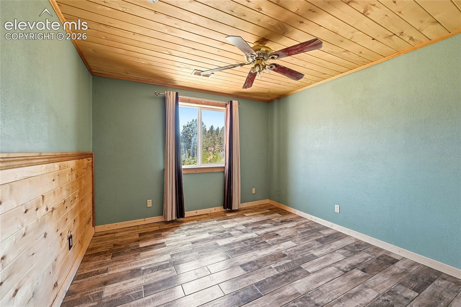 Wood-finish plank ceiling, wood-finish flooring, wood plank wainscoting, and a ceiling fan