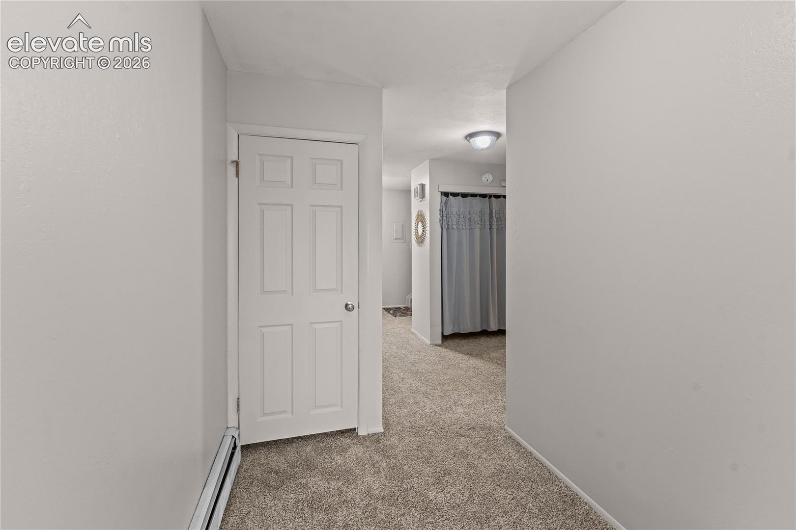 Neutral-toned carpeting, six-panel interior door, and flush-mount lighting fixture