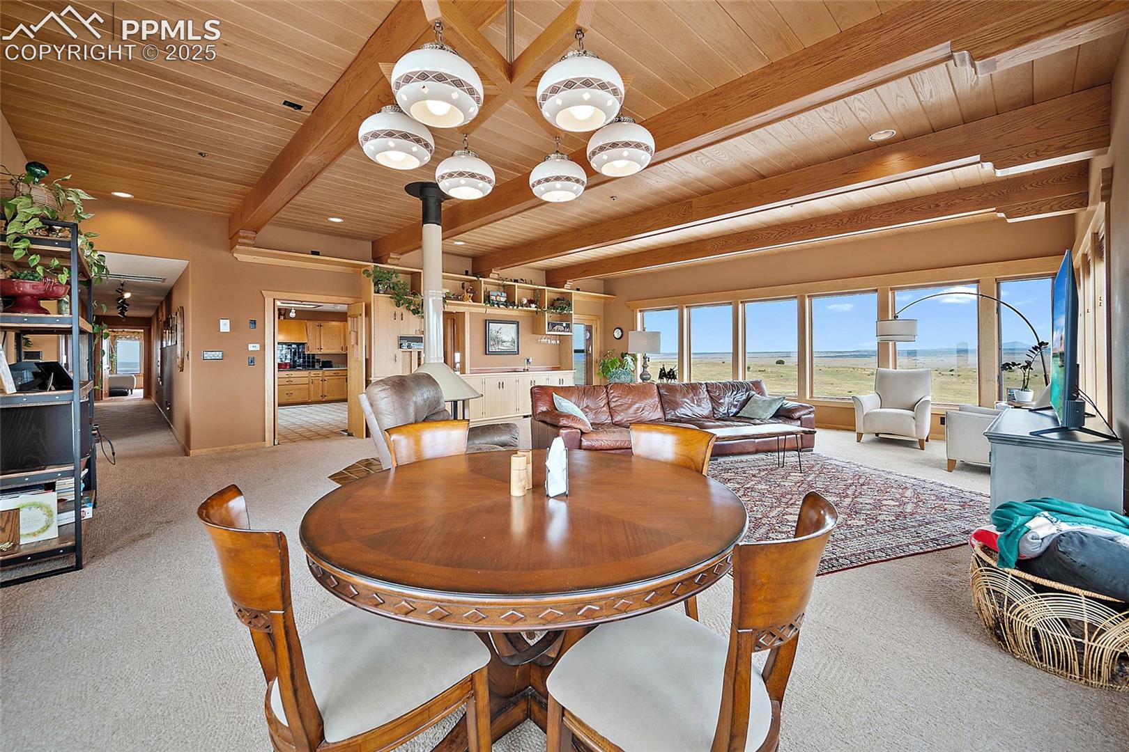 Carpeted dining space with a wood ceiling with exposed beams and baseboards