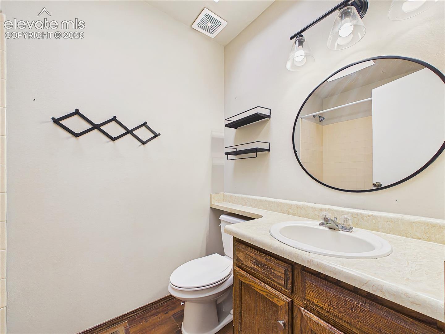 Updated bathroom with a modern round mirror, stylish lighting, and a spacious vanity for added functionality.