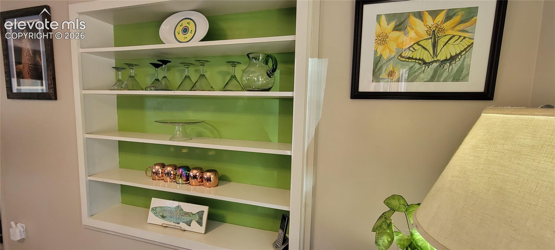 Built-in shelving unit with white shelves and a vibrant green back panel