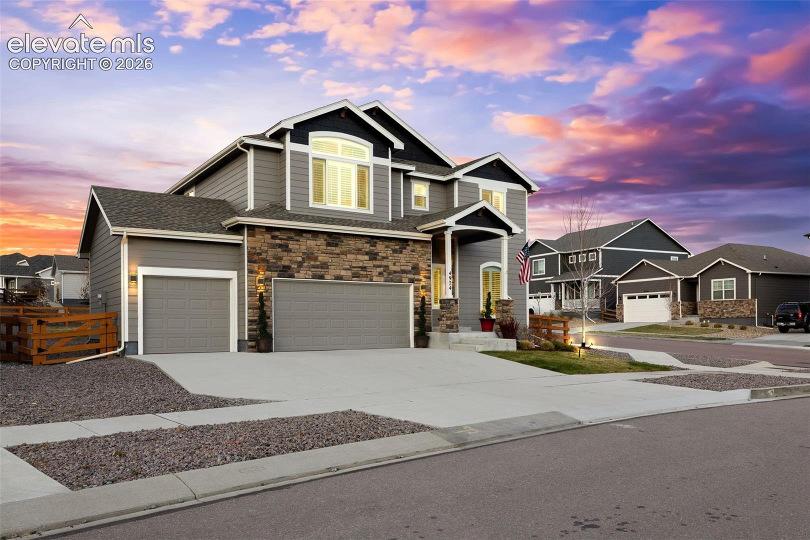 Contemporary exterior with a stone and siding facade, covered front entry, two-car garage, and a concrete driveway