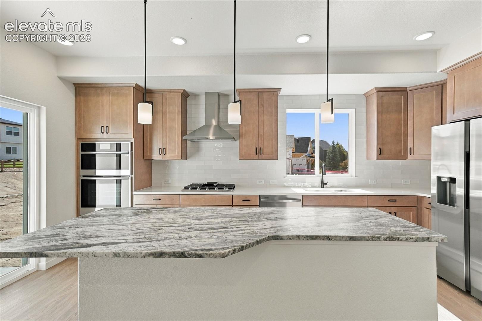 The Kitchen features stainless steel appliances, light maple cabinets with pecan stain, a large kitchen island with quartz countertop, and LVP flooring.