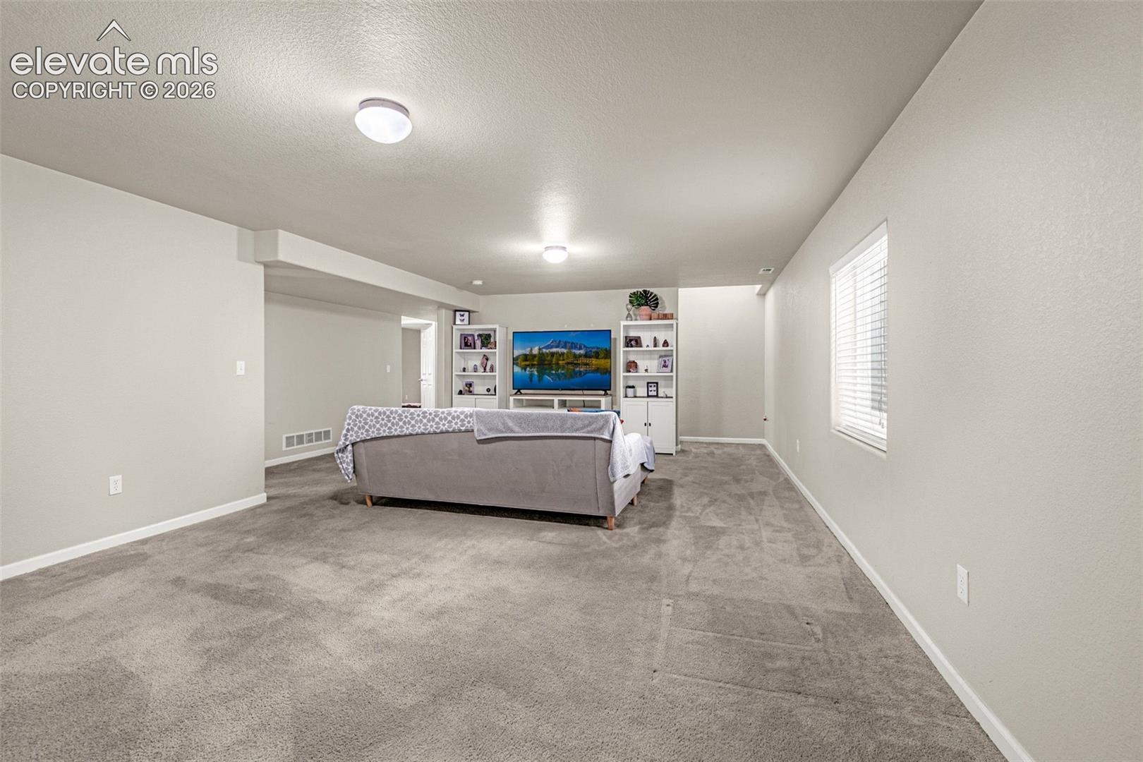 Spacious interior with neutral wall colors, recessed lighting, and a window with blinds