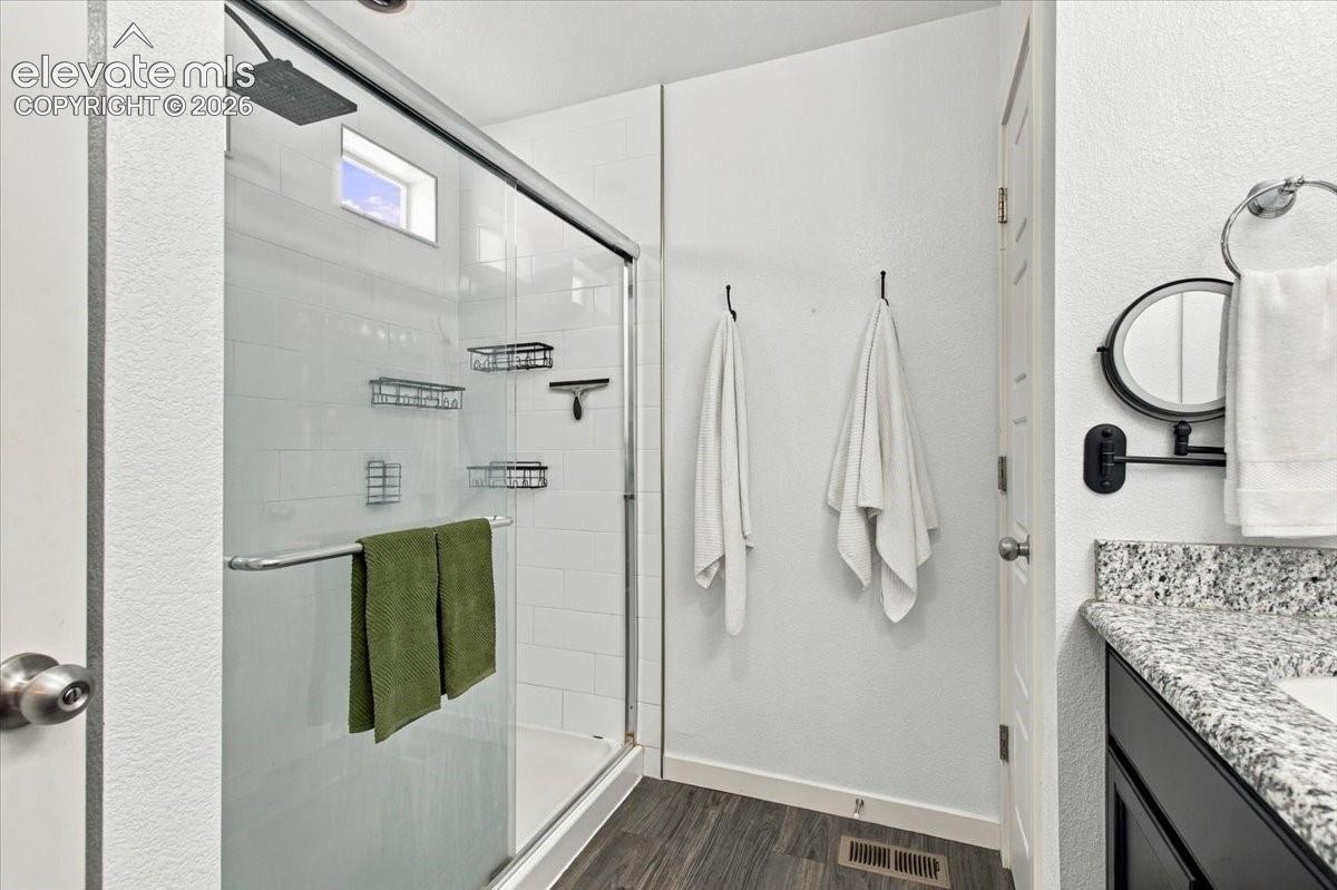 Glass-enclosed shower with a rainfall showerhead, white subway tile surround, and a clerestory window