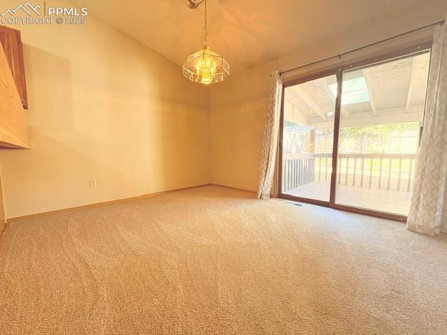 Empty room featuring light colored carpet and a chandelier