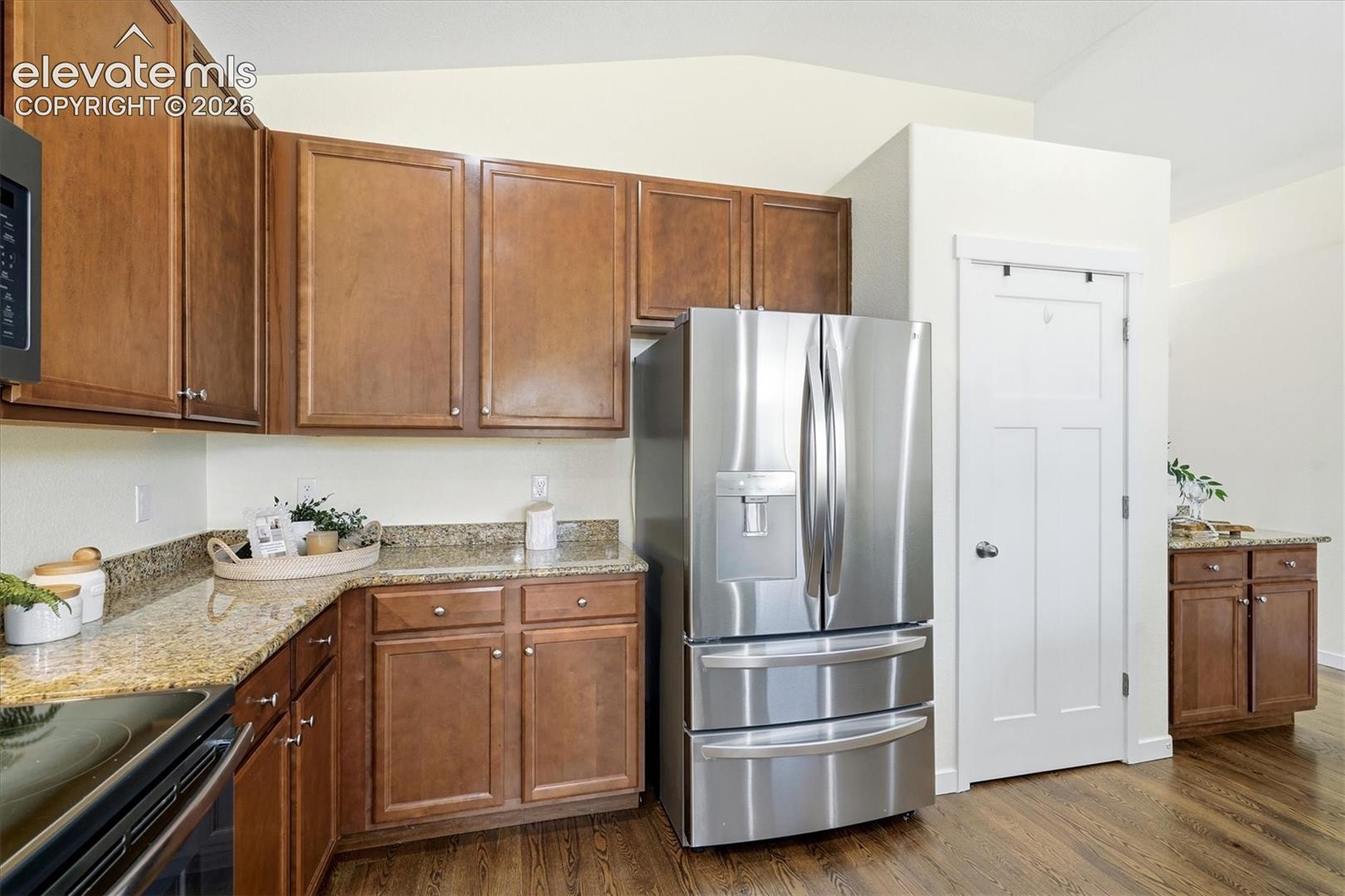 Kitchen featuring wood-finish flooring, granite countertops, and stainless steel appliances