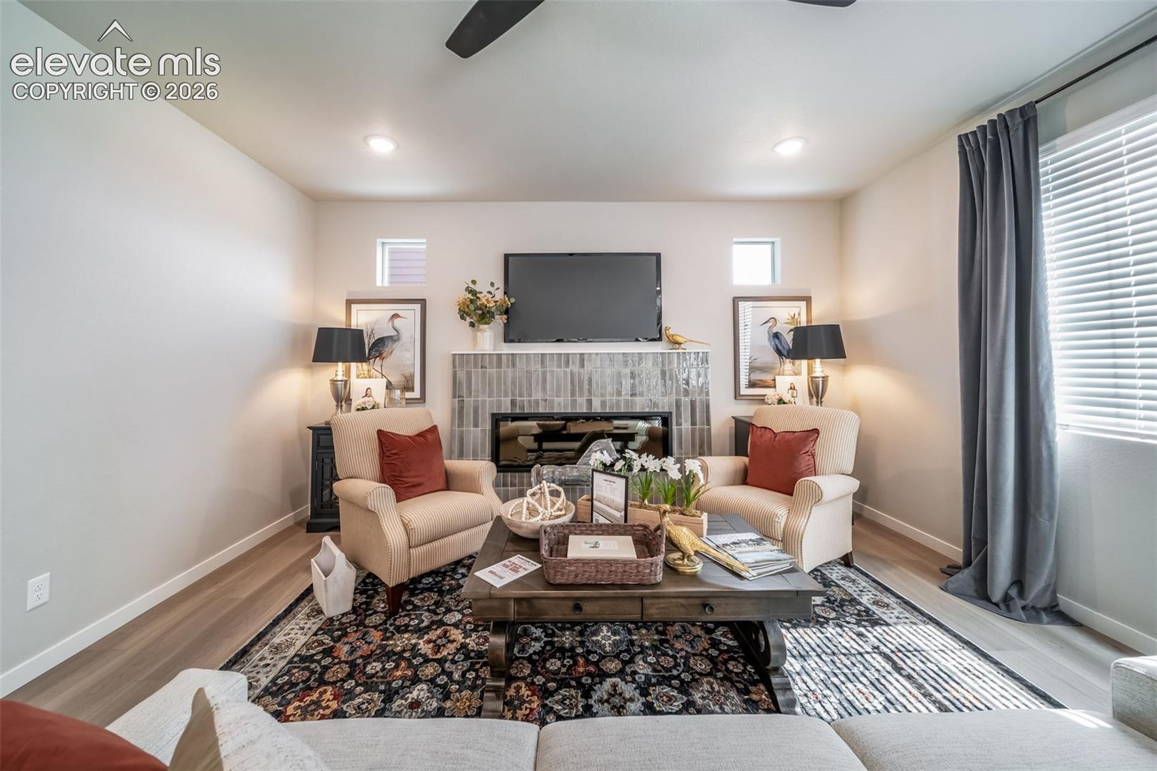 Living area featuring a tiled fireplace with mantel, recessed lighting, and wood-finish flooring
*Photos of a model home*