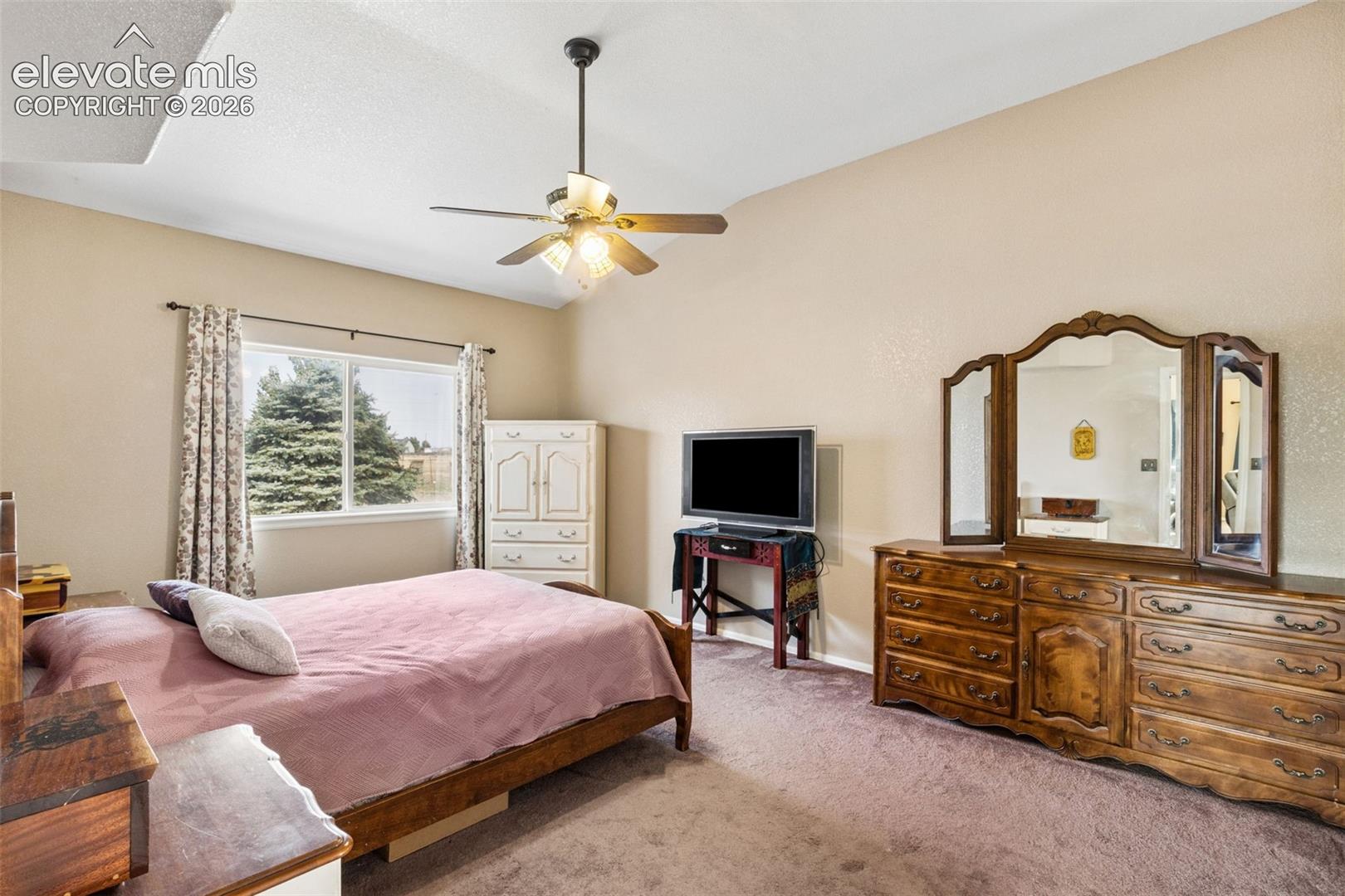Vaulted ceiling with an integrated multi-blade ceiling fan and carpeted flooring