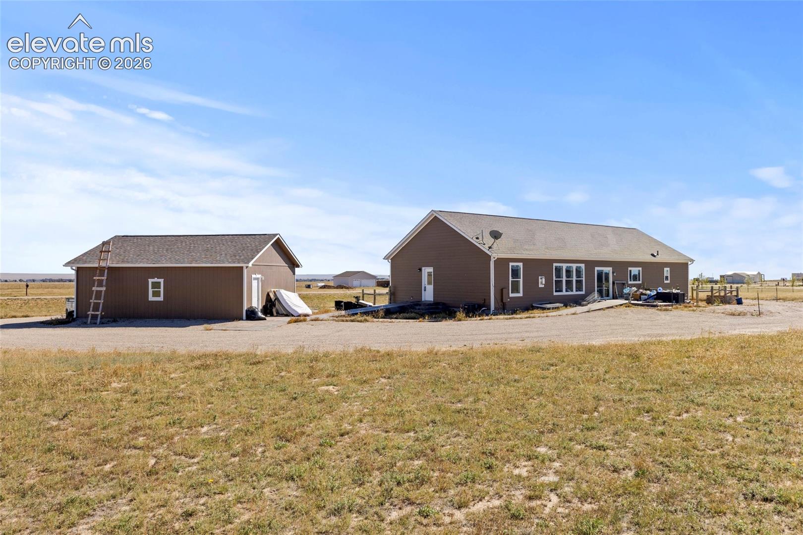 Single-story residence featuring horizontal lap siding, an attached garage structure, and expansive acreage