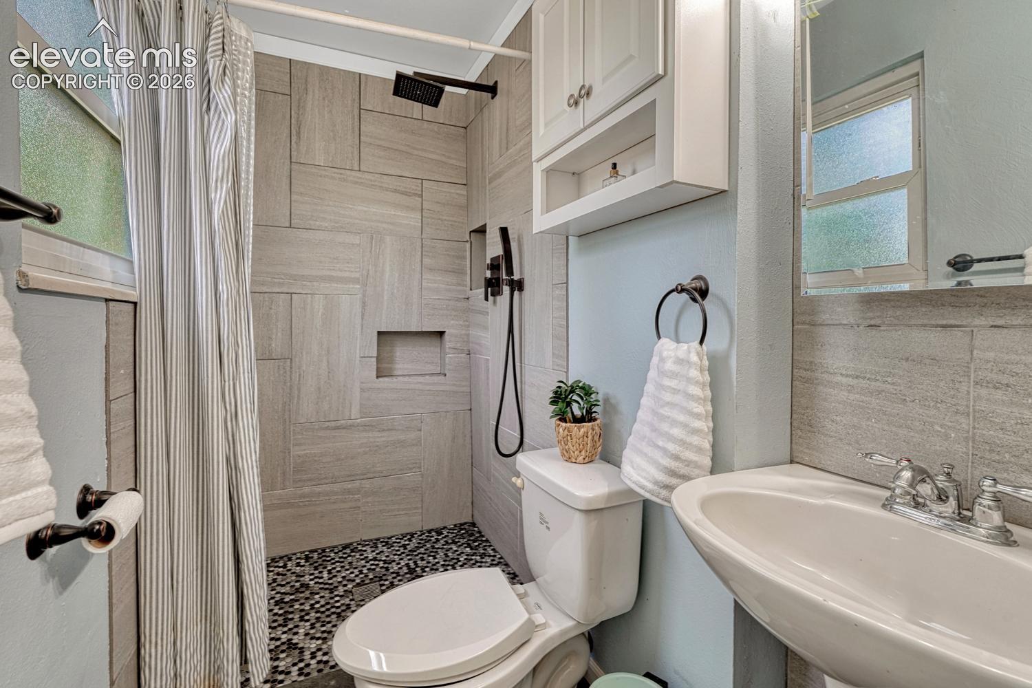 The Primary Bathroom features a pedestal sink, mirror, cabinet, and tiled shower.