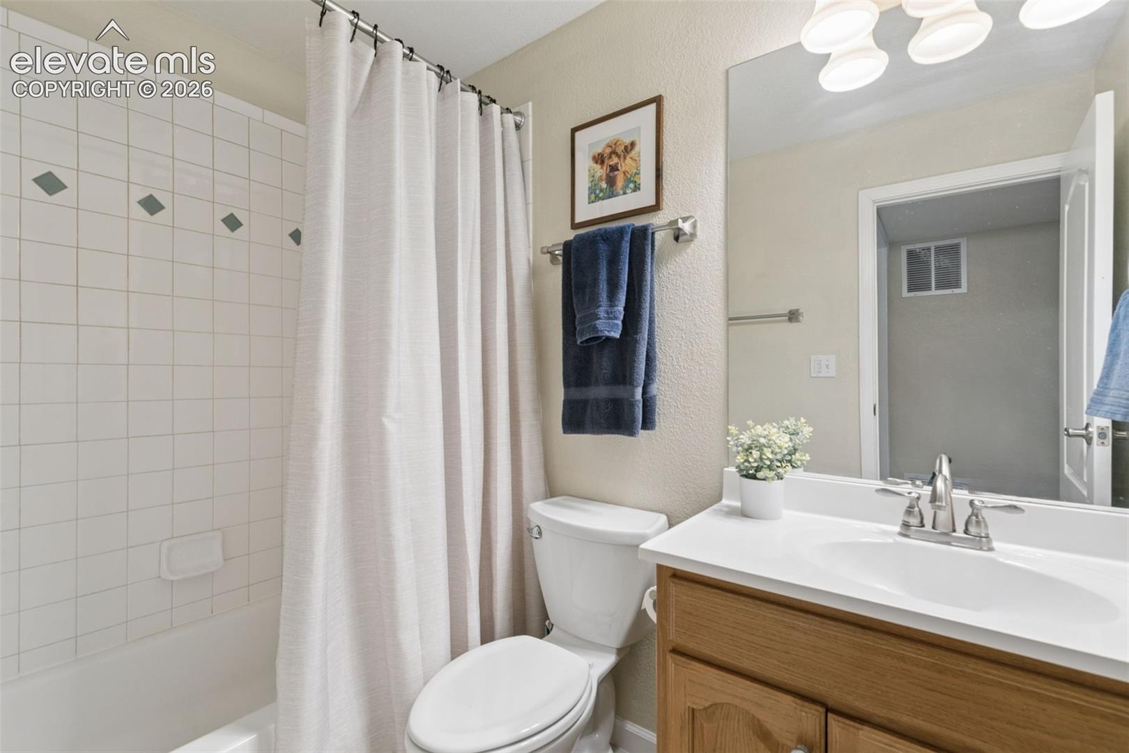 Bathroom featuring a built-in tub with white tile surround, a single vanity with a white countertop and integrated sink, and a chrome faucet