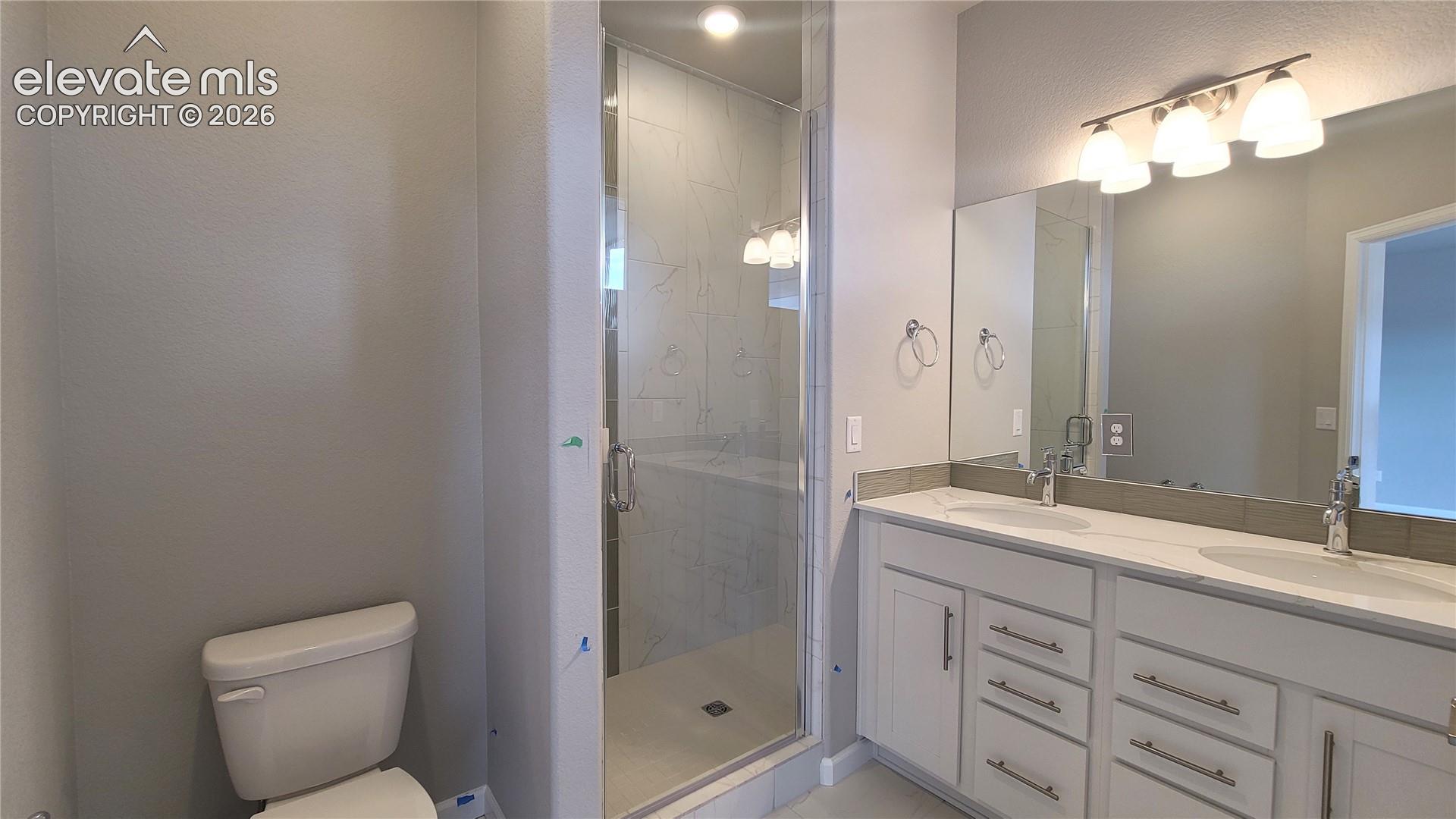 Primary bathroom with quartz countertop, dual vanities, and tile surrounds! 