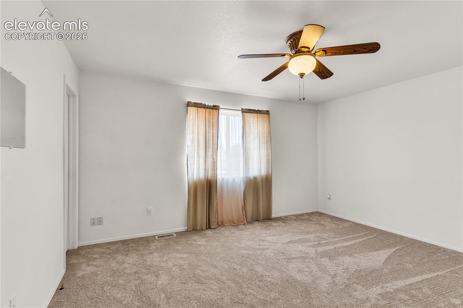 Ceiling fan with integrated lighting, neutral carpet flooring, and window with natural light