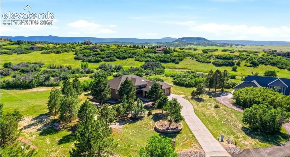Spacious property with a winding driveway, mature trees, and a mountain backdrop
