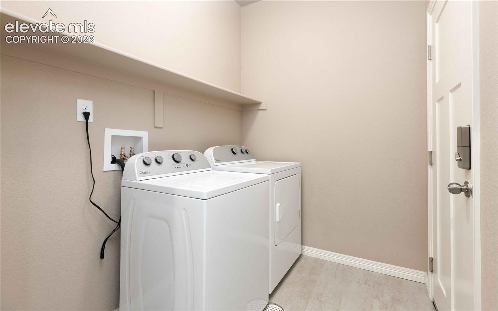 Laundry with built in shelf. Washer and dryer convery, room connects house to the garage