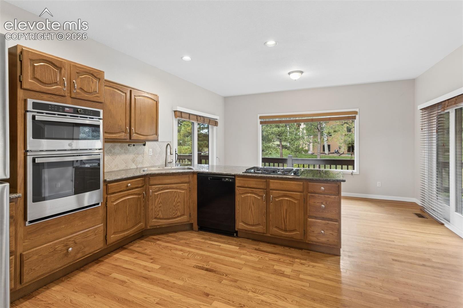 Kitchen featuring wood-finish cabinetry, stainless steel double ovens, a built-in cooktop, and a sliding glass door