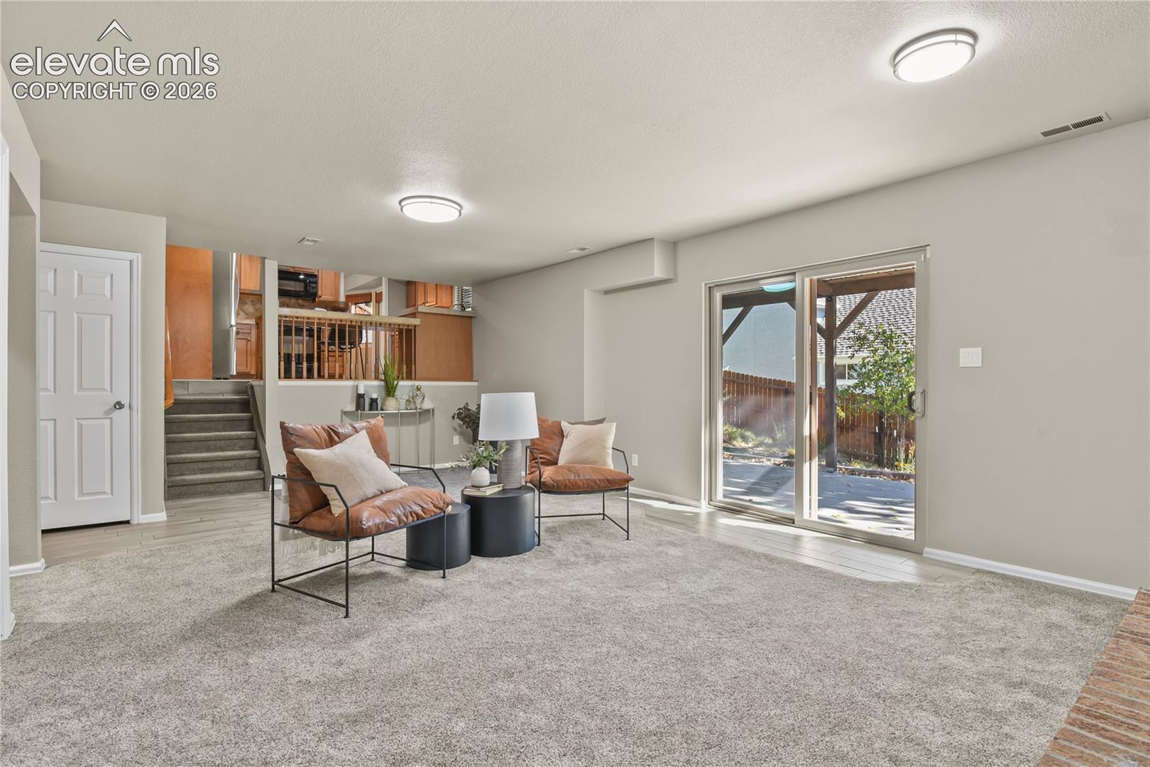 Neutral wall color, carpeted flooring, flush-mount ceiling lighting, and a sliding glass door providing external access