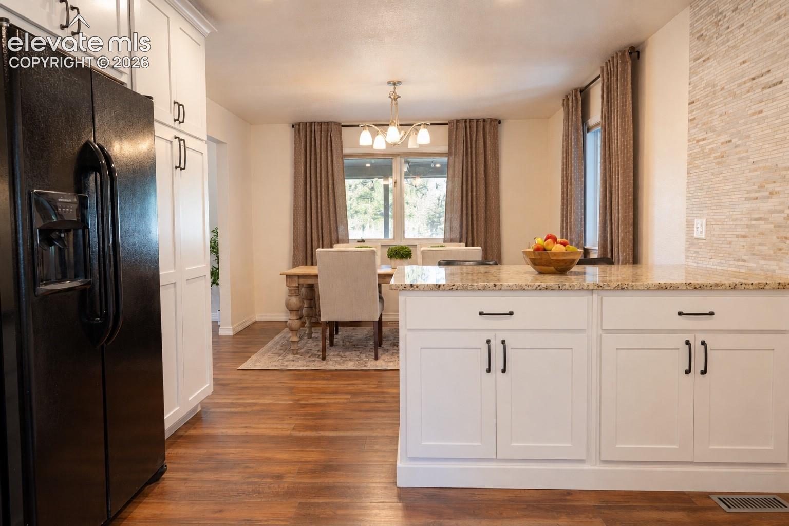 Kitchen featuring white shaker cabinetry, granite countertops, tile backsplash, and wood-finish flooring