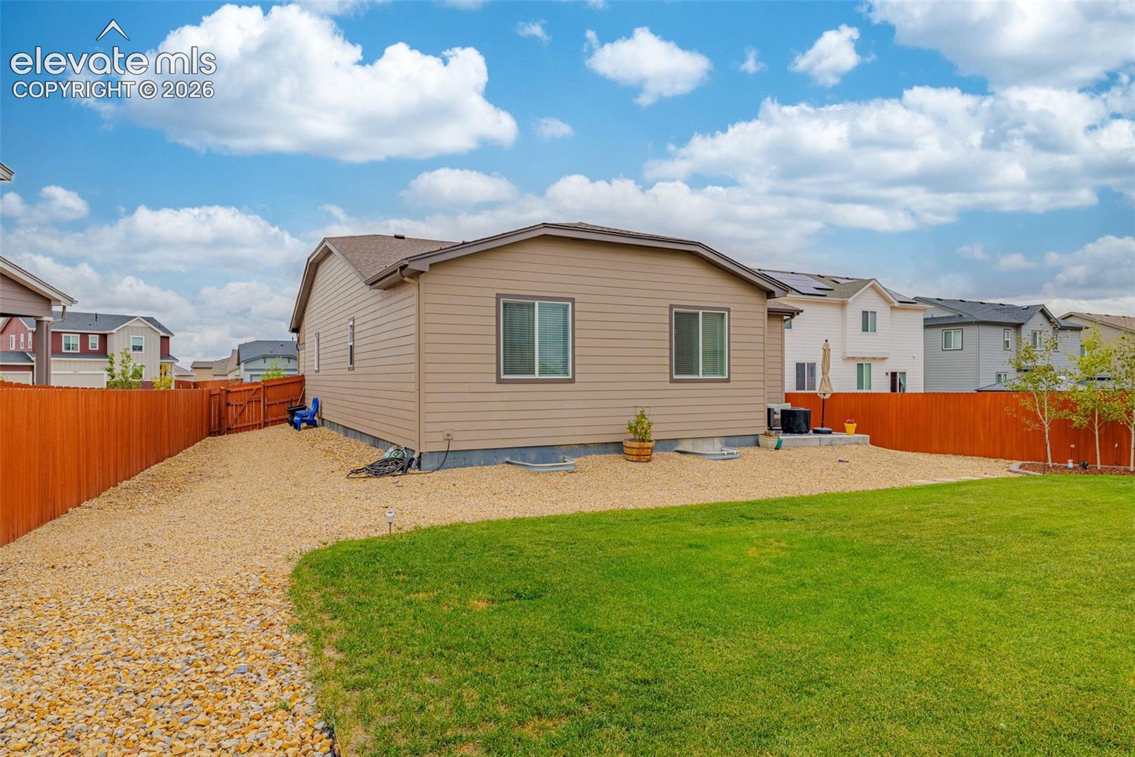 Expansive backyard featuring a manicured lawn, gravel patio, and wood privacy fencing
