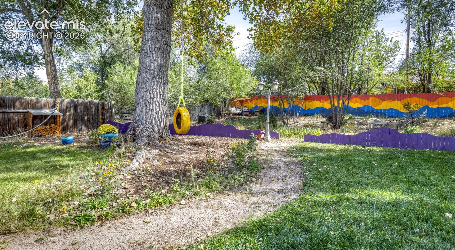 Expansive yard featuring mature trees, a gravel pathway, and a painted privacy fence
