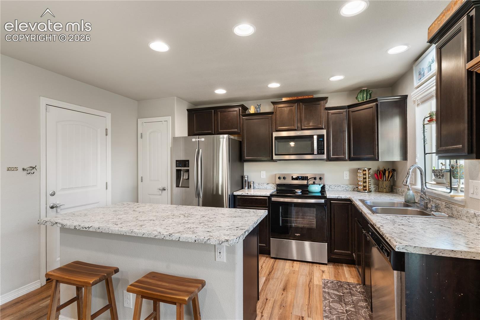 Kitchen featuring dark wood cabinetry stainless steel appliances and a pantry