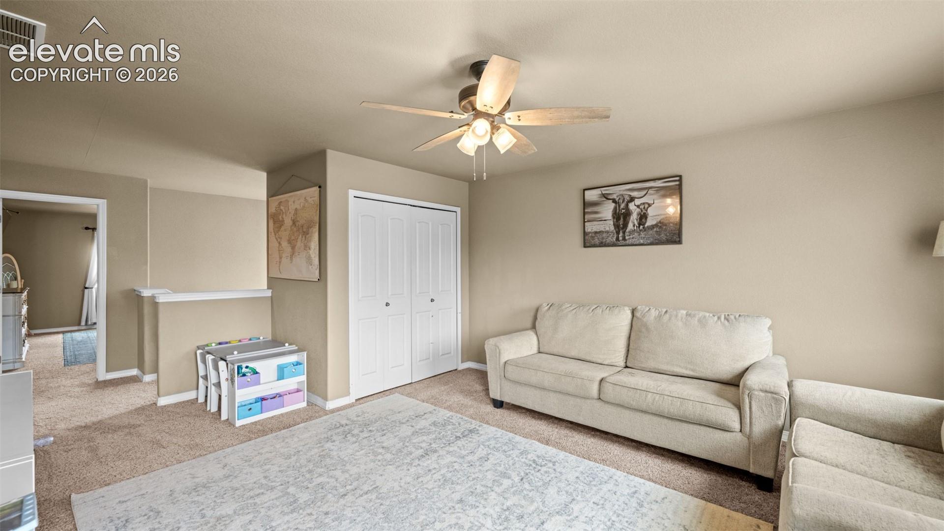 Carpeted interior space featuring a ceiling fan with integrated lighting, bi-fold closet doors, and neutral wall paint