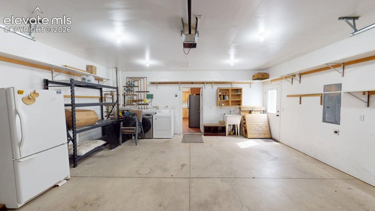 Concrete flooring with overhead lighting, utility sink, and built-in shelving