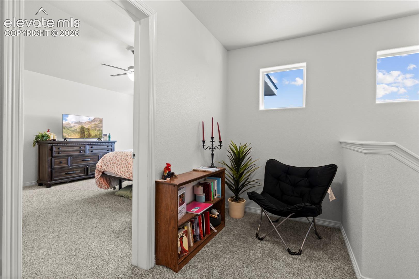 Neutral-toned wall paint, carpeted flooring, two square windows, and an arched entryway