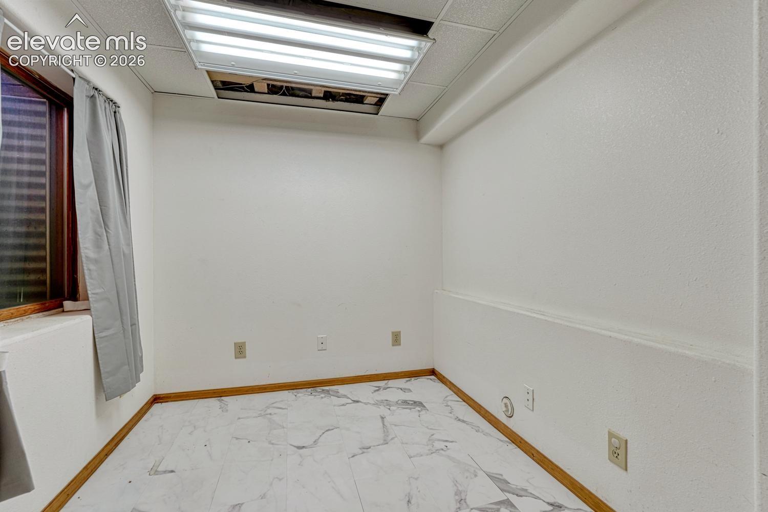 Bright, versatile interior space featuring recessed ceiling lighting, wood-trim flooring with marble-finish detailing, and multiple electrical outlets throughout