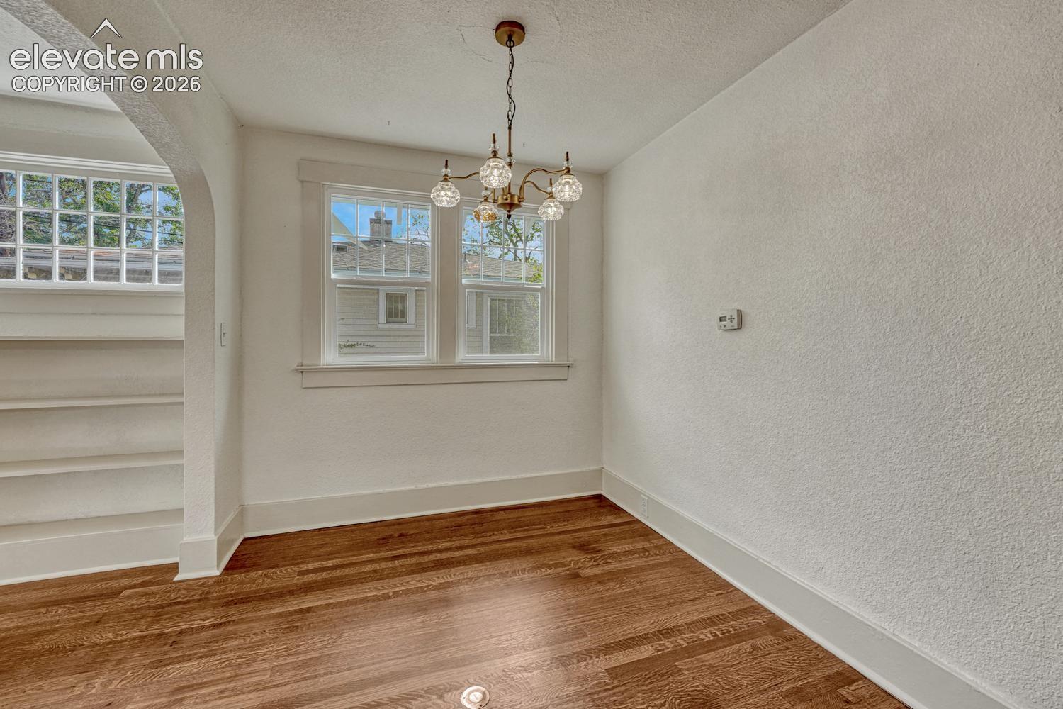Hardwood flooring, arched doorway, multi-pane windows, brass-finish chandelier